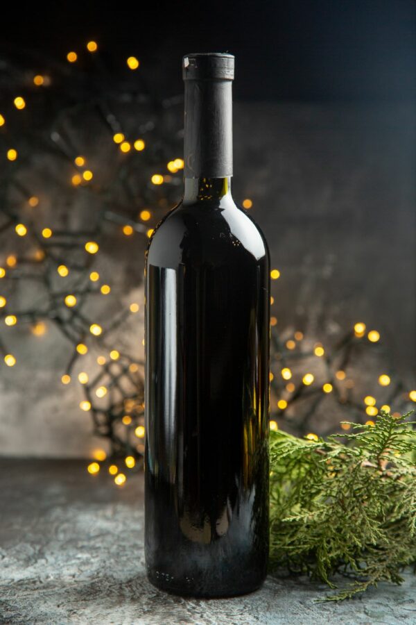 Image représentant une bouteille de vin noir avec des guirlandes lumineuses derrière en décor